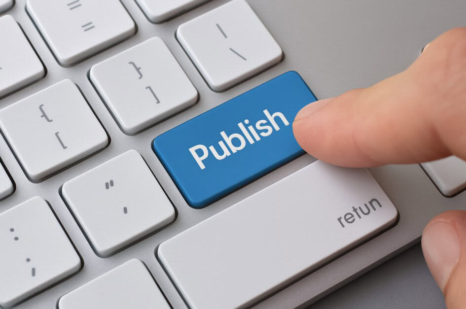 Close-up van een vinger die op een blauwe "Publish"-toets van een toetsenbord drukt, met focus op de publicatieactie.